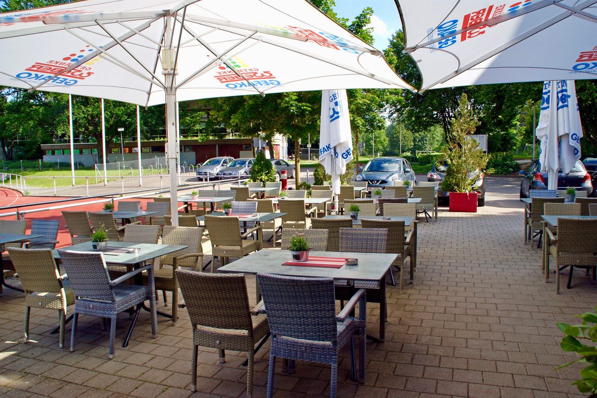 Sommerterrasse mit weißen Sonnenschirmen und gedeckten Tischen